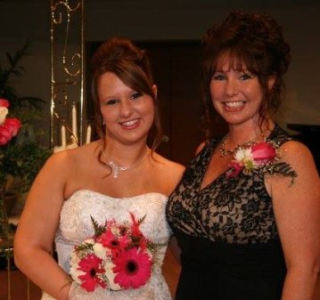 Bride smiling alongside a woman in a black lace dress
