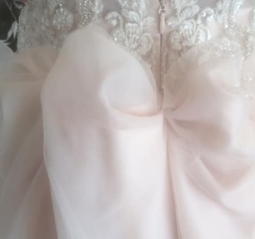 Close-up of a blush pink dress bodice with a lace and bow detail
